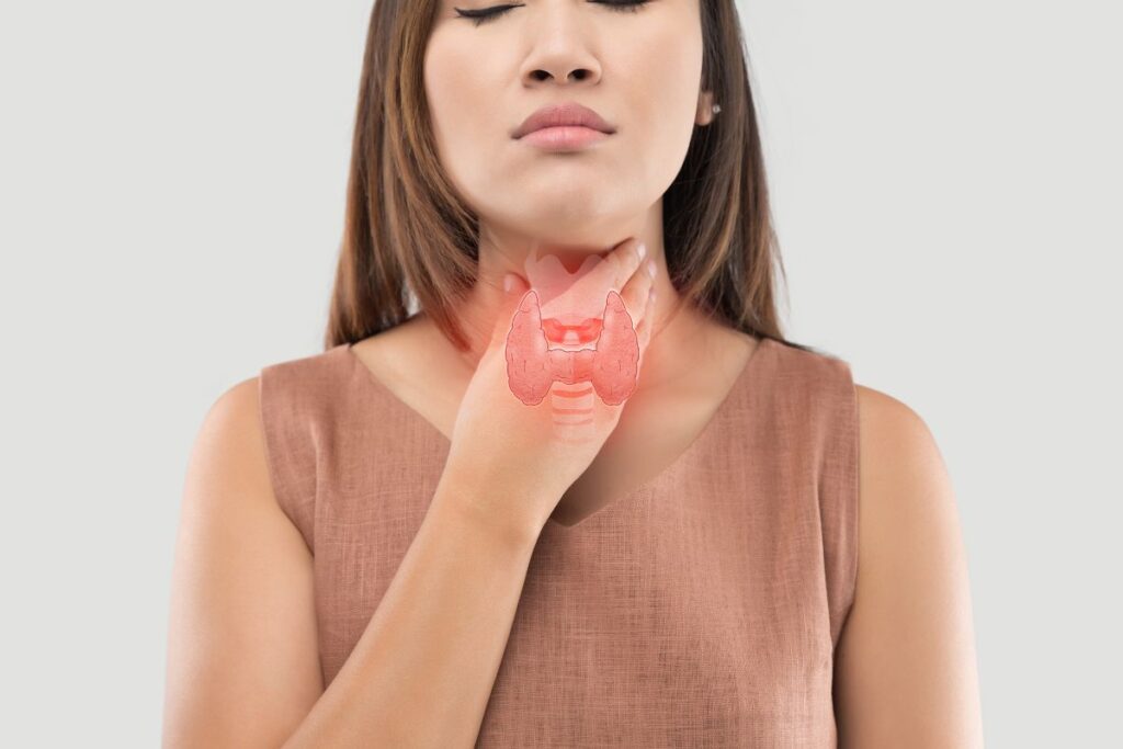 Woman holding her throat showing where the thyroid is located